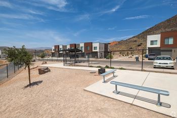 A park with a bench and a tree in front of a building.